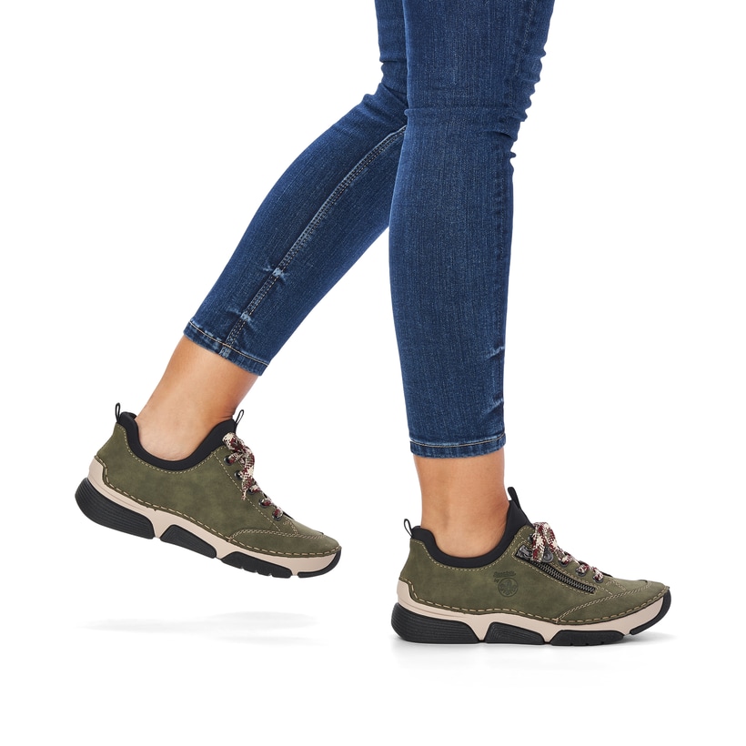 Khakigrüne Rieker Damen Slipper 45973-54 mit Elastikeinsatz sowie einer leichten Sohle. Schuh am Fuß.
